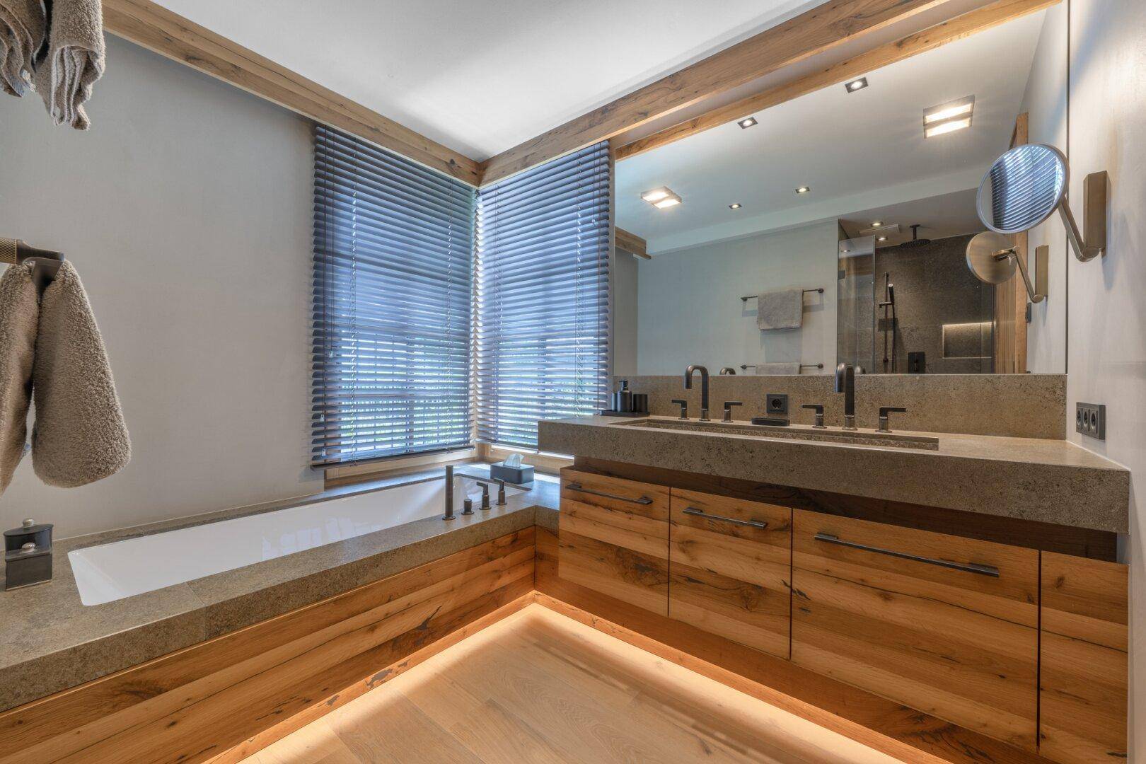 Geräumiges Badezimmer mit Badewanne, Doppelwaschbecken und Holzdetails, hell und modern gestaltet.