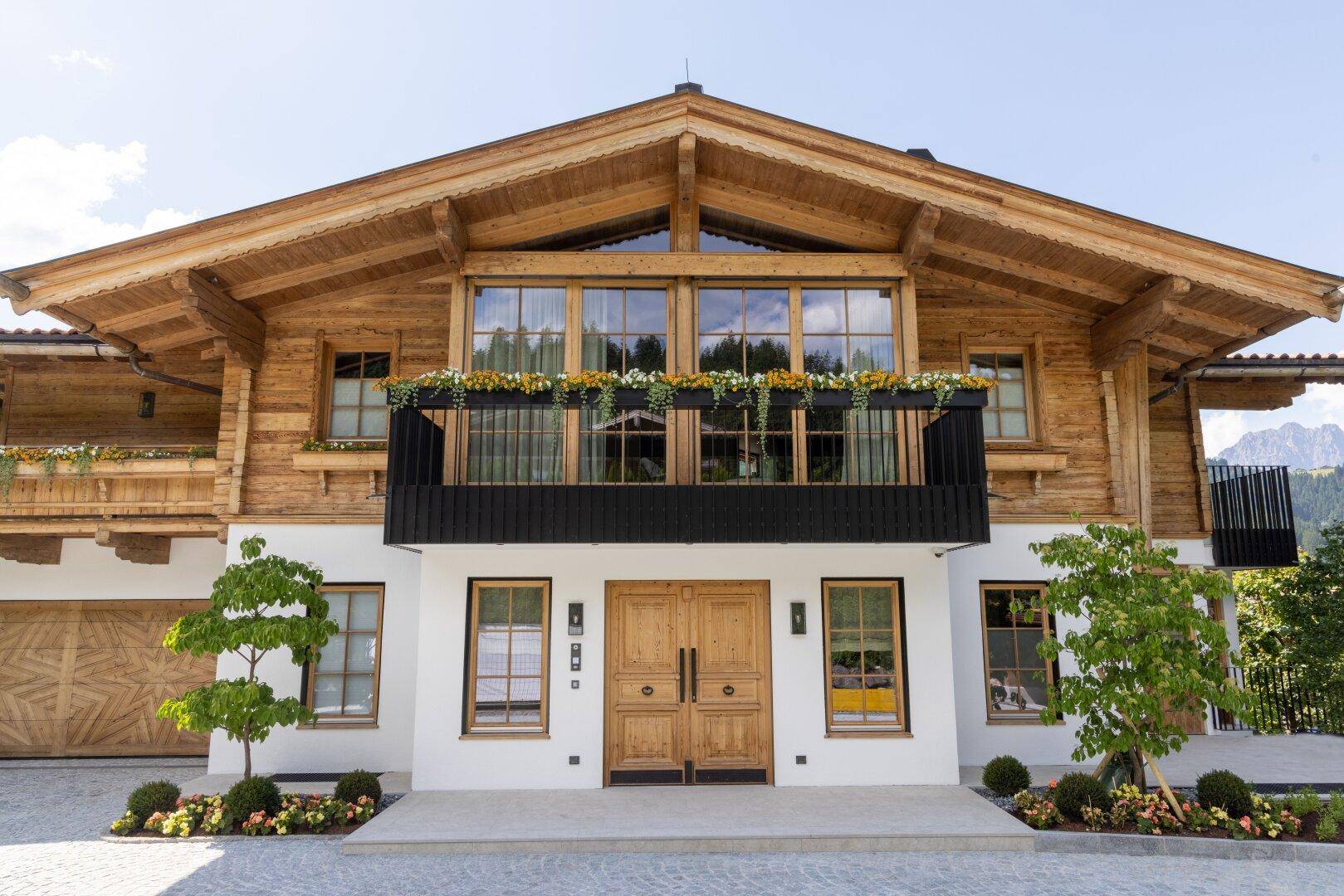 Frontansicht des modernen Chalets mit großen Fenstern, Holzbalkonen und alpiner Architektur.