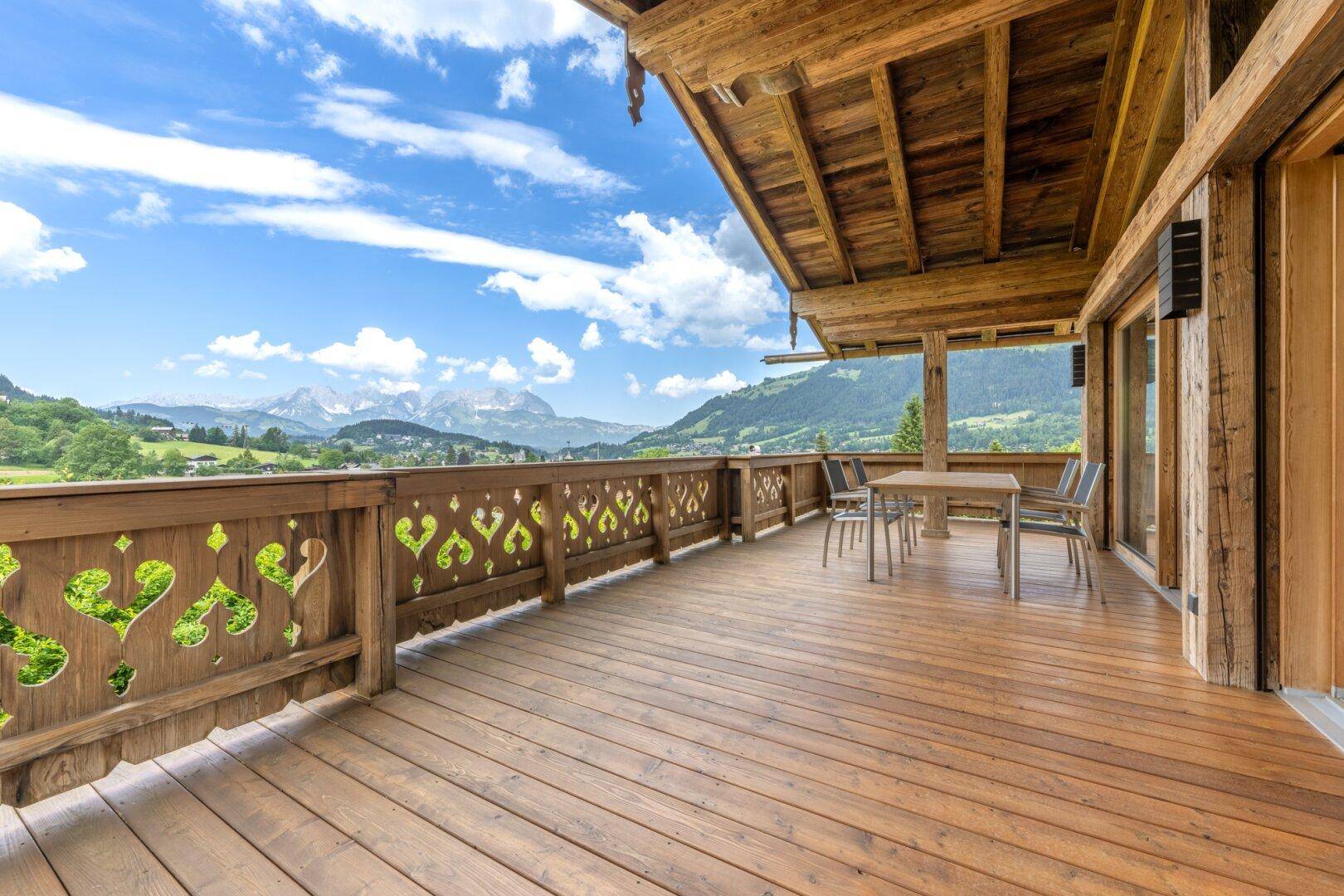 Geräumiger Holzbalkon mit Essbereich und atemberaubendem Panoramablick auf die Berge.