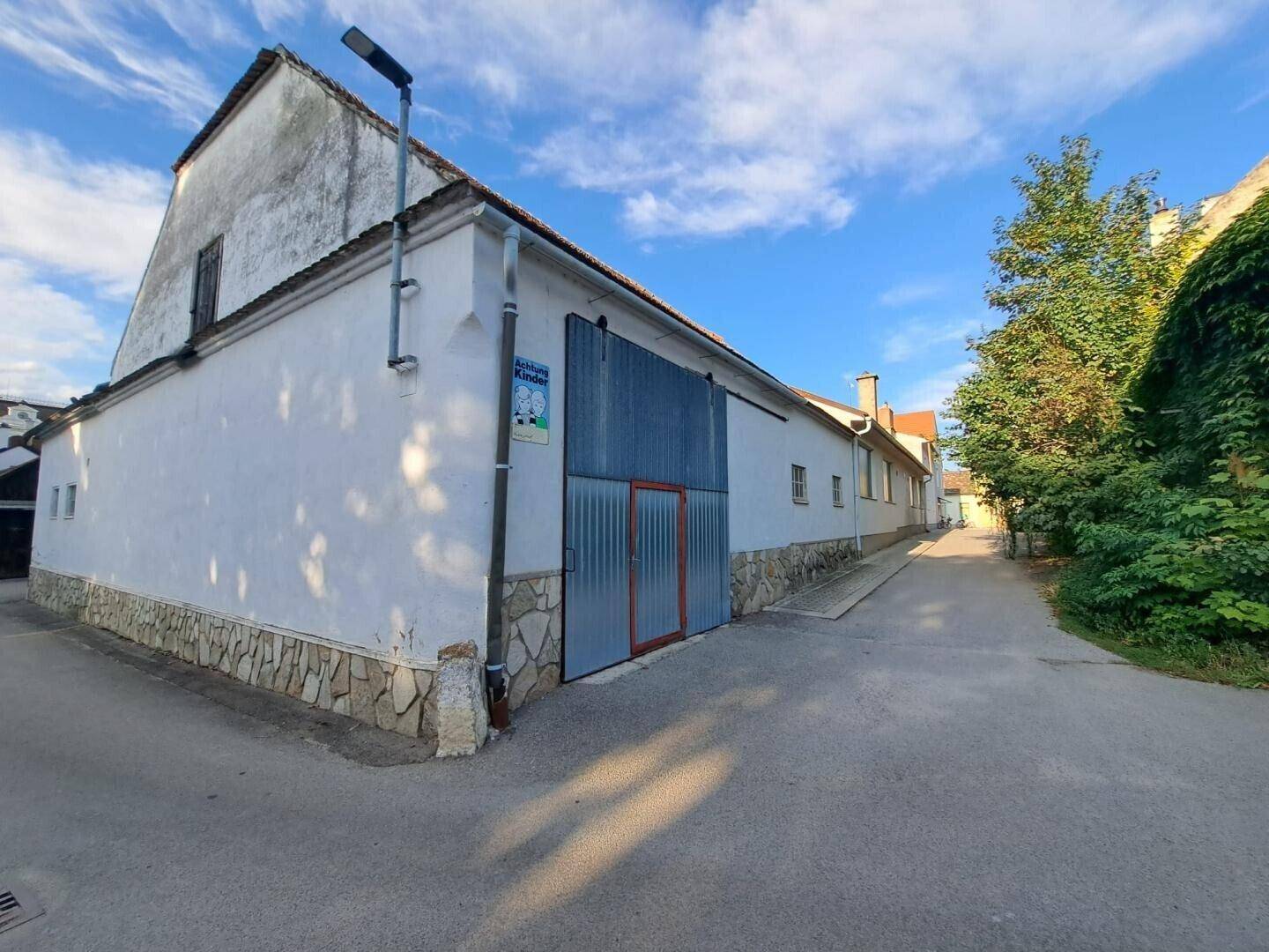 Historisches Nebengebäude mit großen Toren und gepflastertem Zugangsweg.