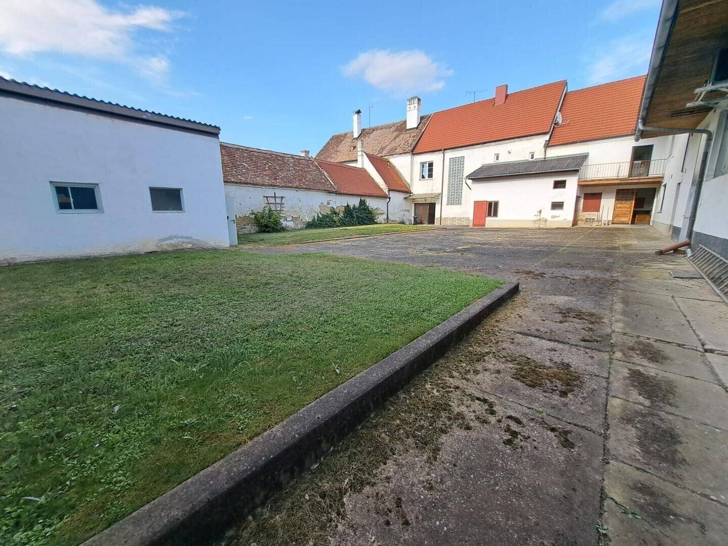 Großer Innenhof mit Rasenfläche und gepflastertem Bereich, umgeben von historischen Gebäuden.