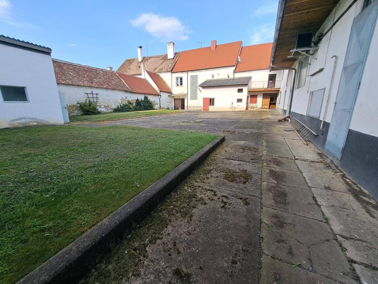 Großer Innenhof mit Rasenfläche und gepflastertem Bereich, umgeben von historischen Gebäuden.