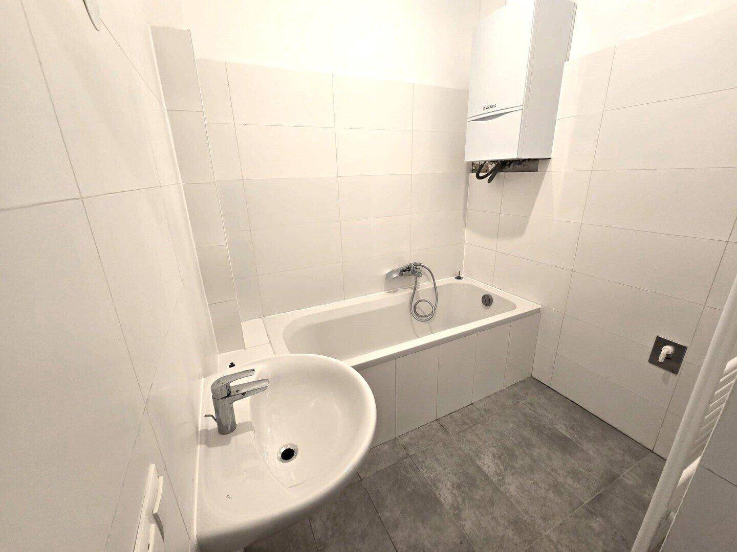 Modernes Badezimmer mit Badewanne, Waschbecken und Wandfliesen in Weiß.