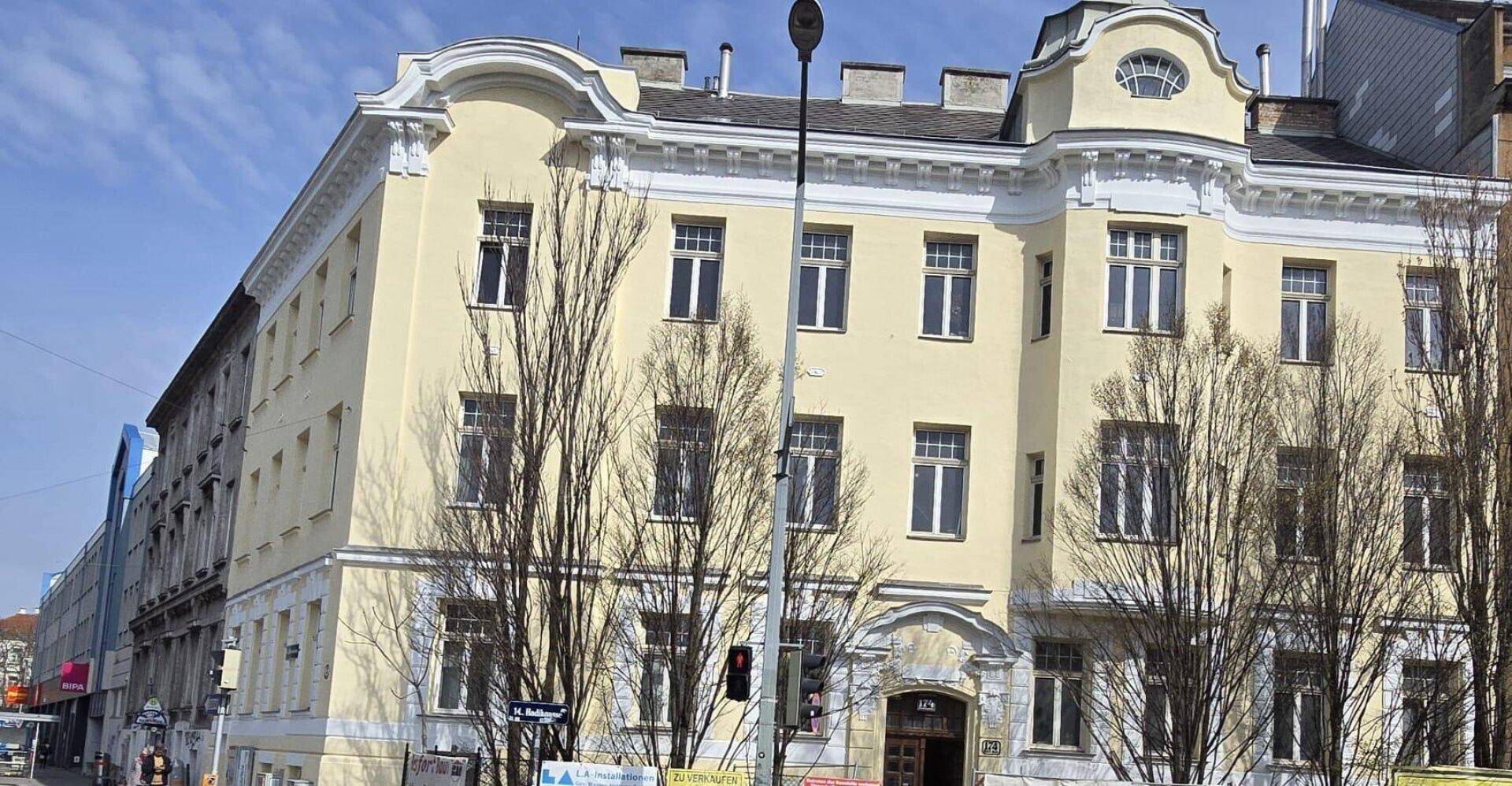 Historisches Gebäude mit gelber Fassade und klassischer Architektur in städtischer Umgebung.