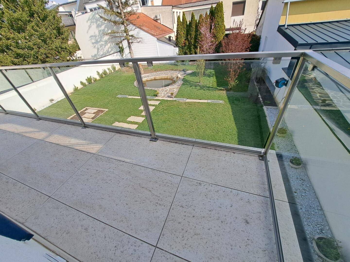 Blick von der Terrasse auf den gepflegten Garten mit Teich und Rasenfläche.
