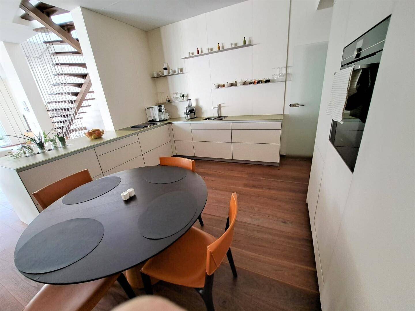 Moderne Küche mit Essbereich, Holzboden und integrierten Geräten.