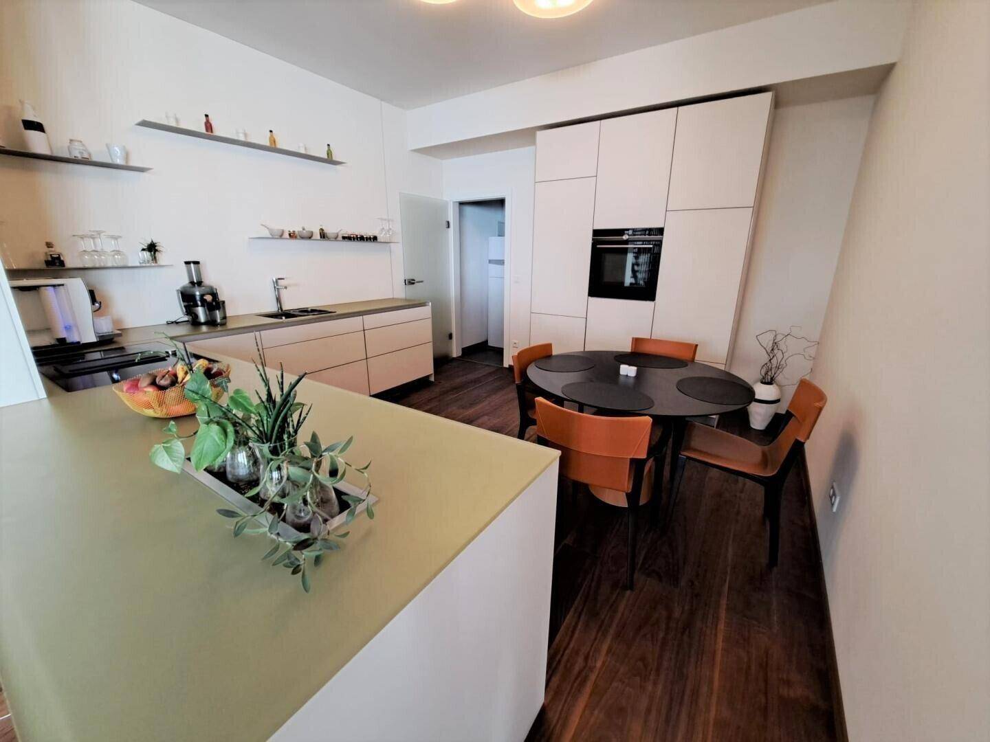 Moderne Küche mit Essbereich, Holzboden und integrierten Geräten.