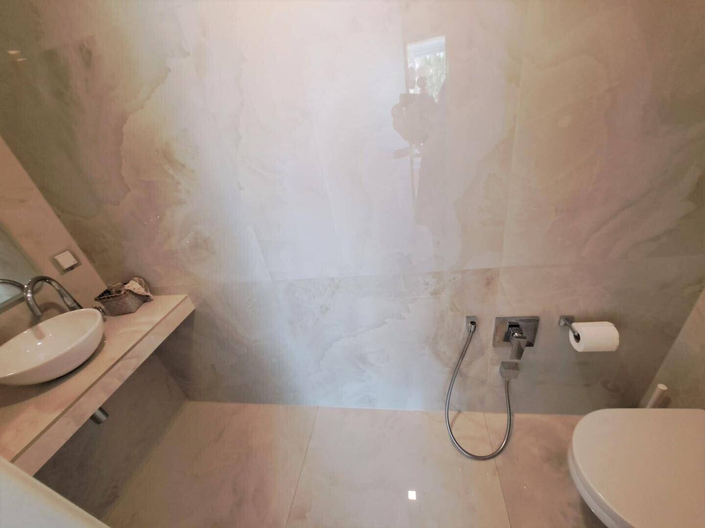 Modernes Badezimmer mit WC, Waschbecken und Duschbrause.