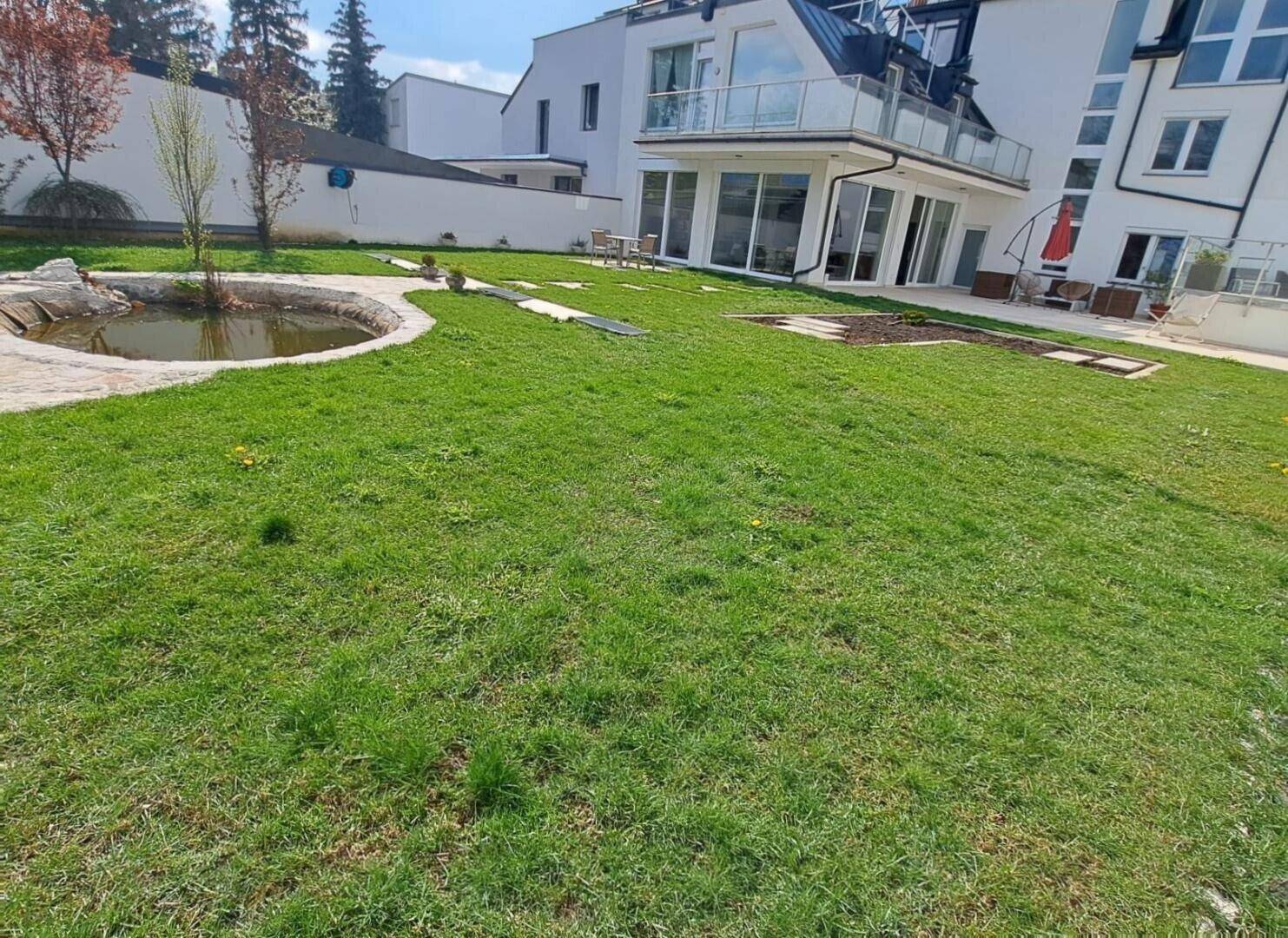 Großer, sonniger Garten mit Teich und Rasenfläche, ideal zum Entspannen.