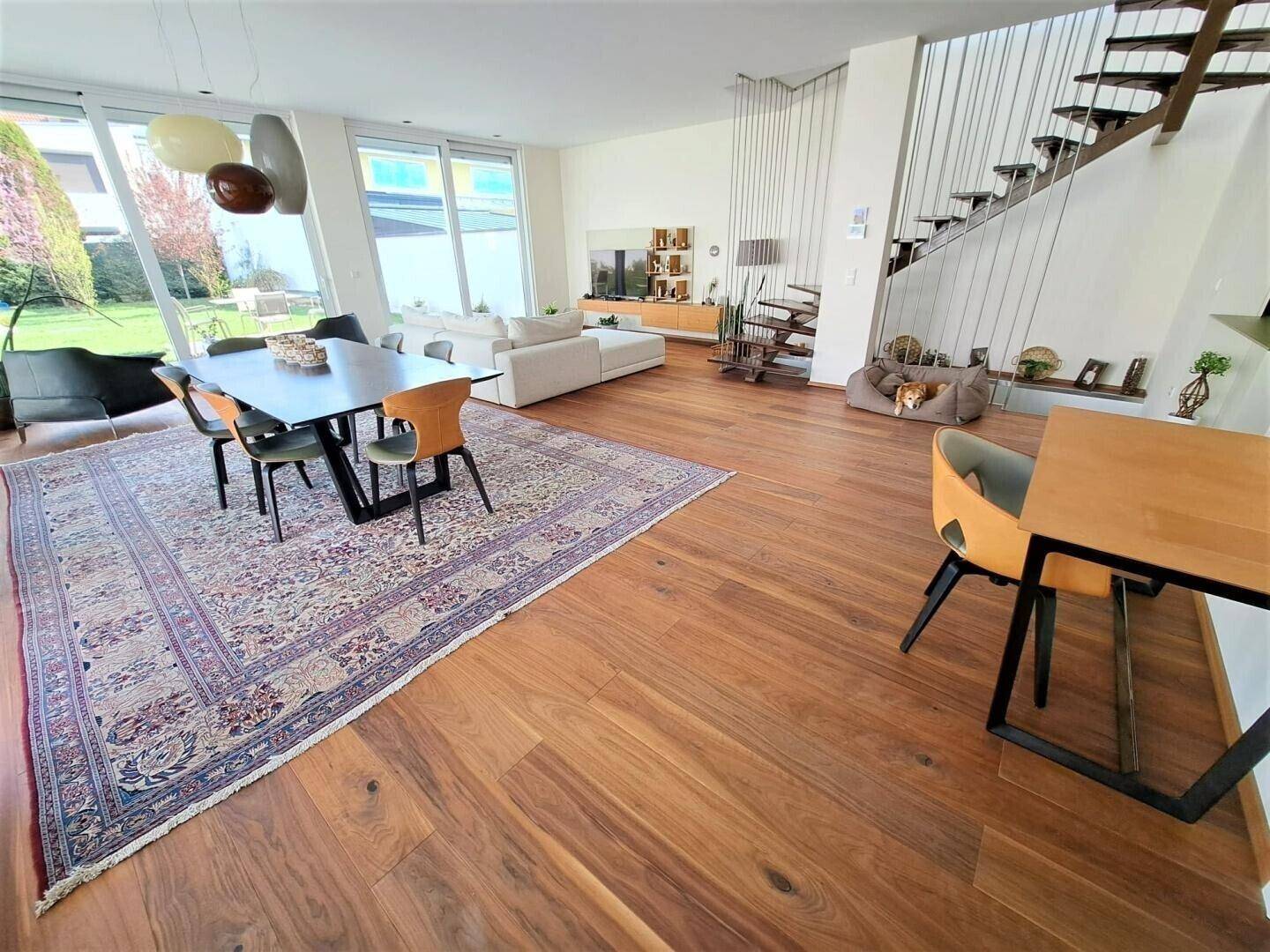 Geräumiger offener Wohn- und Essbereich mit Holzboden, moderner Einrichtung und Treppe.
