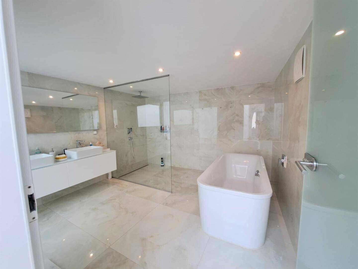Luxuriöses Badezimmer mit freistehender Badewanne, großer Dusche und Doppelwaschbecken.