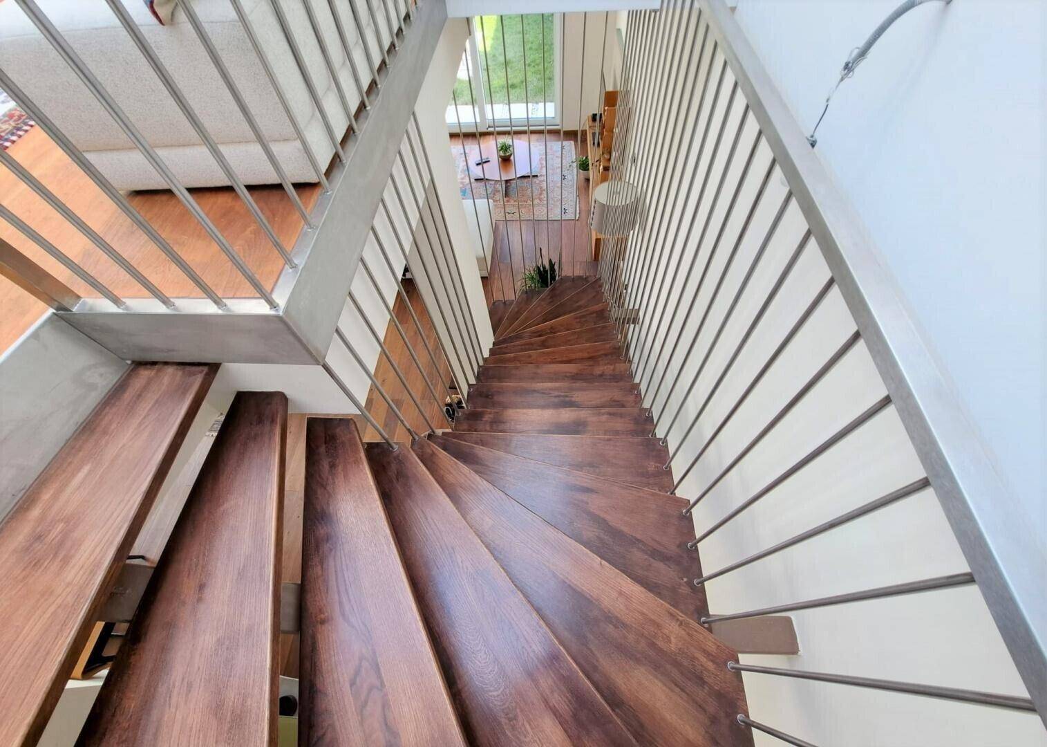 Elegante Holztreppe mit Metallgeländer, die die verschiedenen Ebenen des Hauses verbindet.