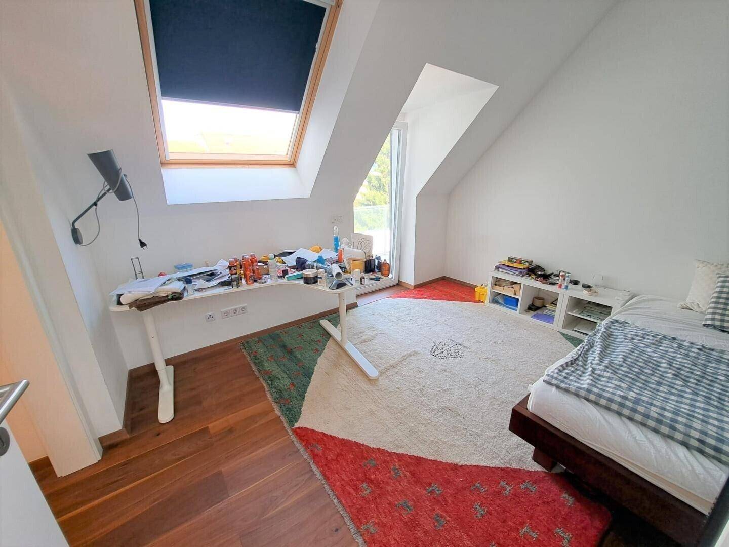 Helles Zimmer mit Dachschräge, Holzboden und Dachfenster für viel Tageslicht.