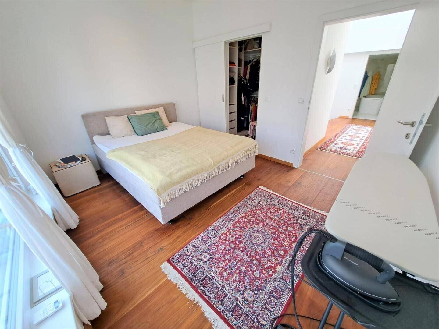 Gemütliches Schlafzimmer mit Holzboden, Teppich und Zugang zu einem begehbaren Kleiderschrank.