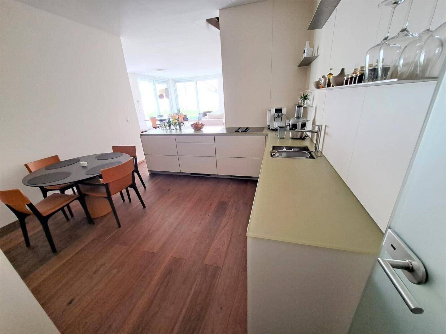 Moderne Einbauküche mit Essbereich, Holzboden und viel Arbeitsfläche.