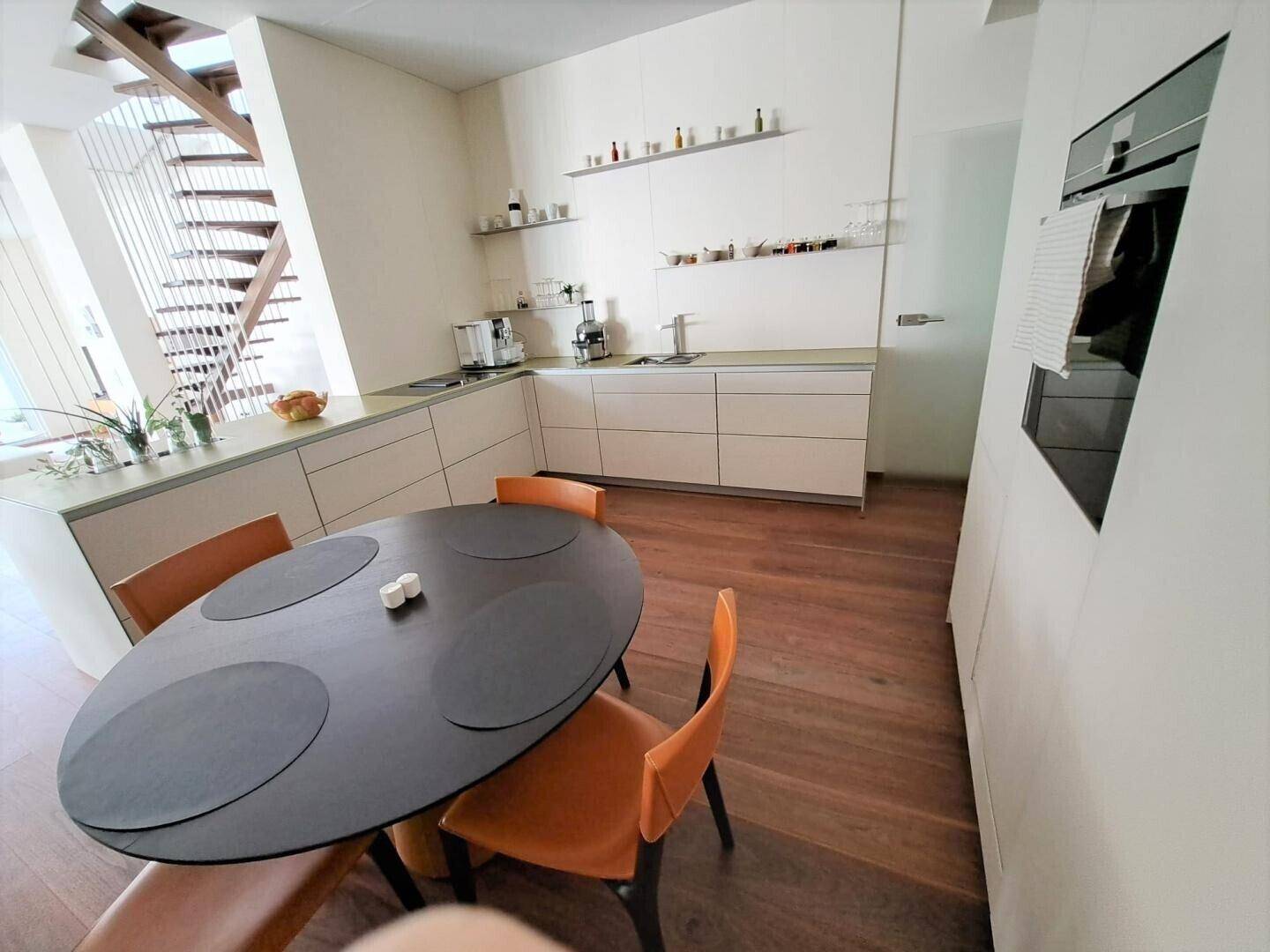 Moderne Küche mit Essbereich, Holzboden und integrierten Geräten.
