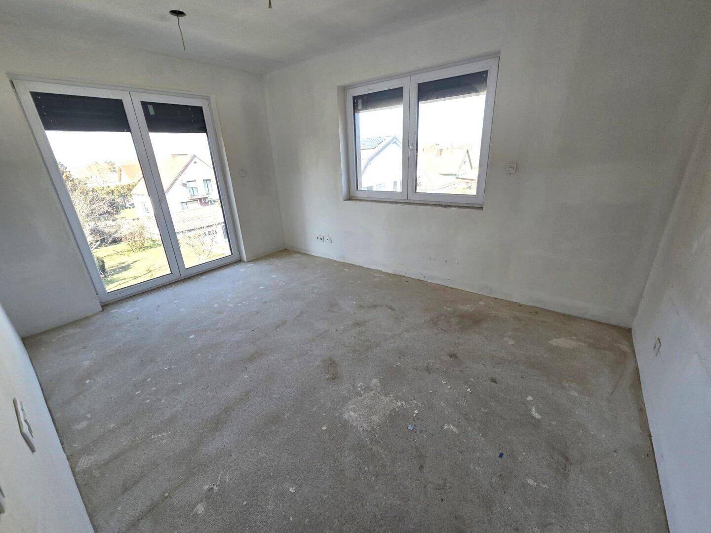 Unfertiges Schlafzimmer mit großen Fenstern und viel natürlichem Licht.
