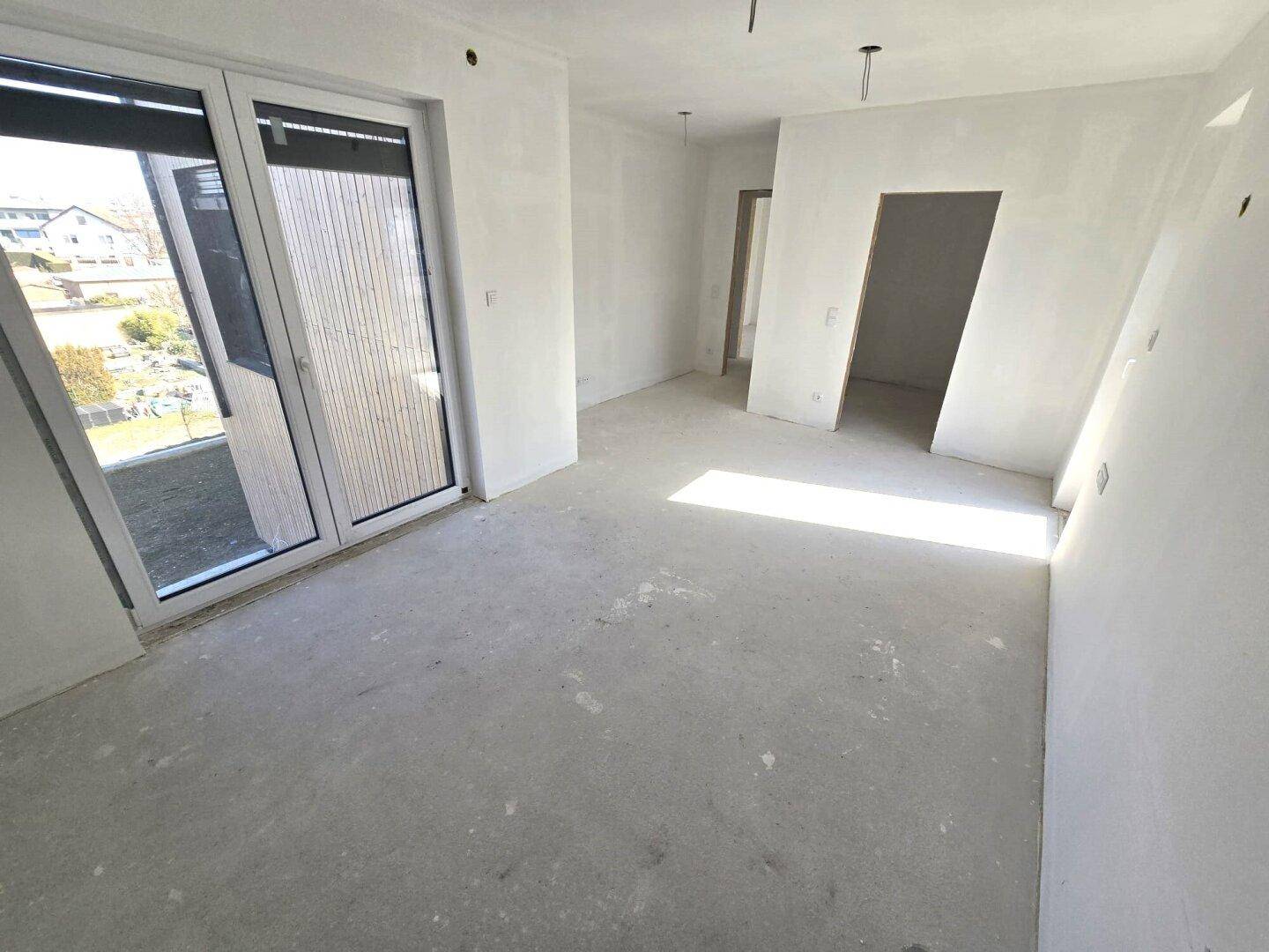 Geräumiges, unfertiges Schlafzimmer mit Zugang zu einem Außenbereich und viel Licht.
