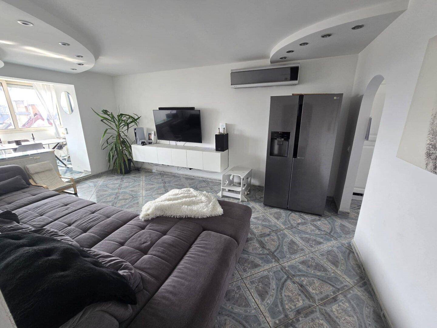 Modernes Wohnzimmer mit großem Sofa, Fernseher, Klimaanlage und Fliesenboden.