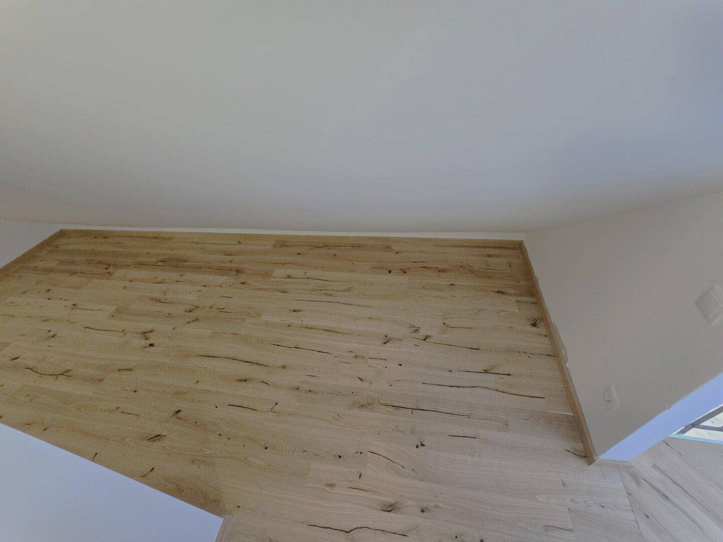 Detailansicht des hellen Laminatbodens und der weißen Wände in einem modernen Raum.