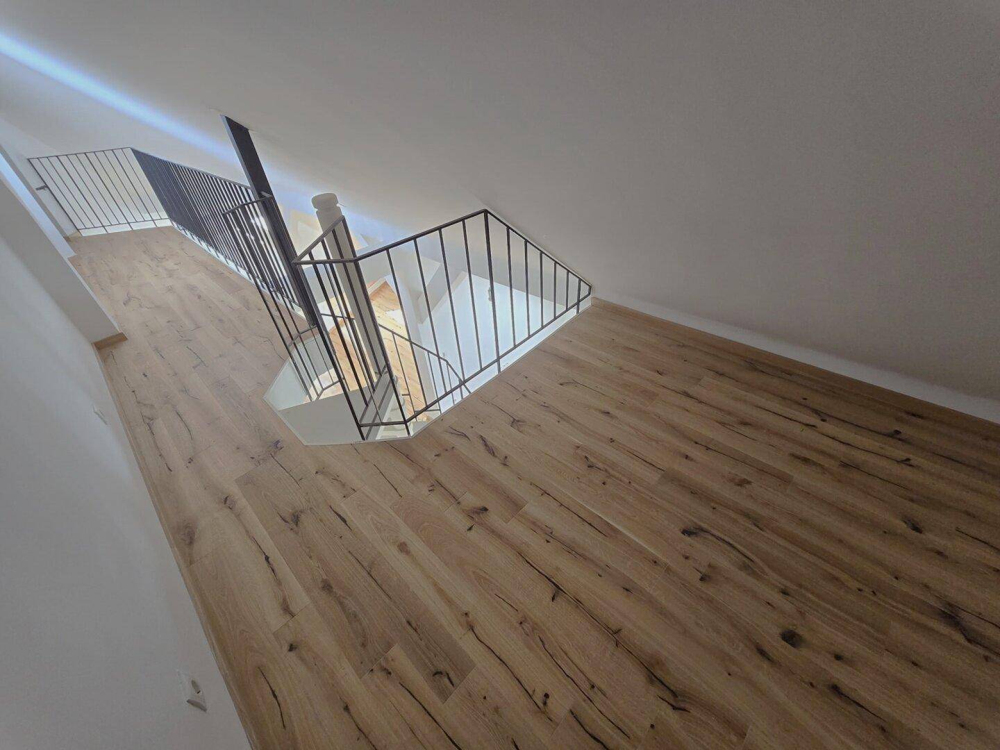 Oberer Flurbereich mit Holzboden und Blick auf die Wendeltreppe nach unten.