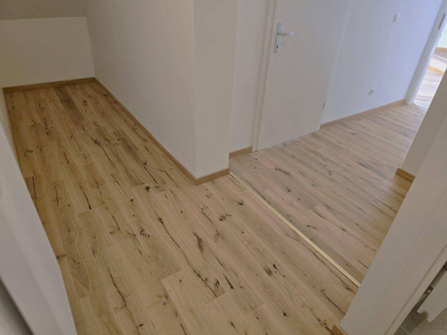 Heller Flur mit Laminatboden und weißen Türen, der zu weiteren Räumen führt.