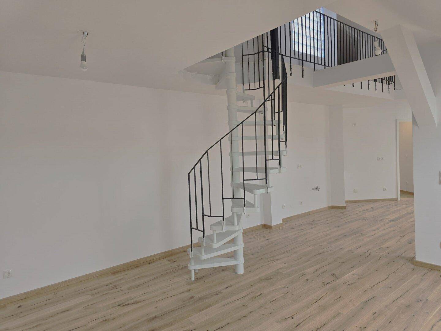 Heller Innenraum mit einer eleganten weißen Wendeltreppe und Holzboden.