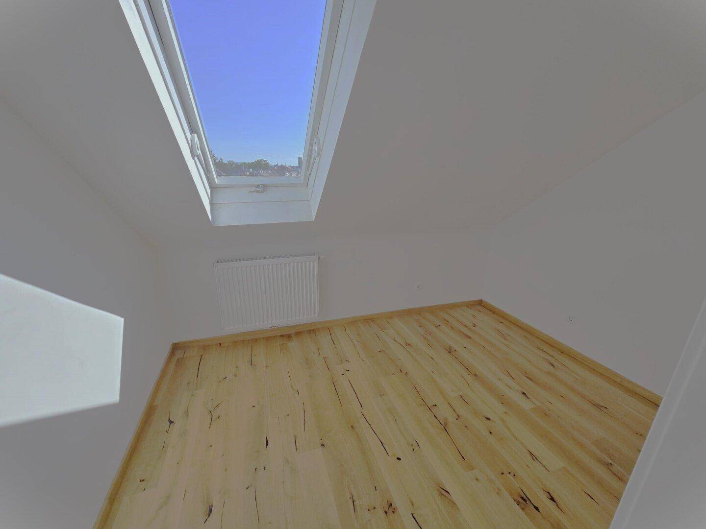 Heller Innenraum mit Laminatboden und einem großen Dachfenster, das viel Licht spendet.
