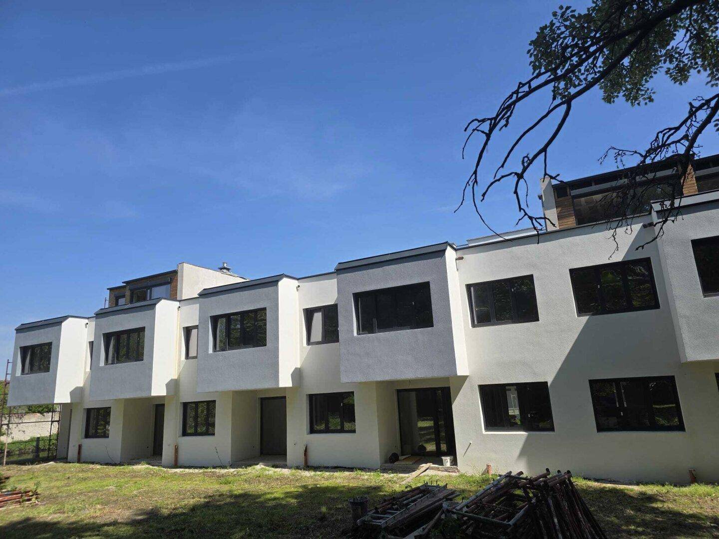 Fassade eines Neubaus mit modernen Fenstern und klaren Linien, noch im Bau befindlich.