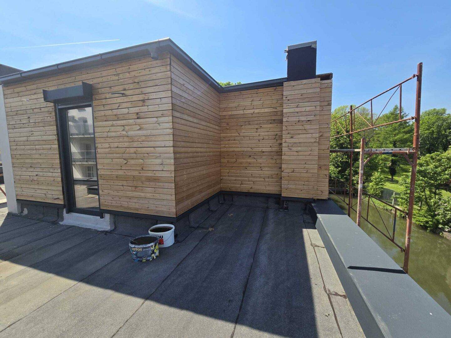 Dachbereich mit Holzverkleidung und Baugerüst, noch im Bau befindlich.