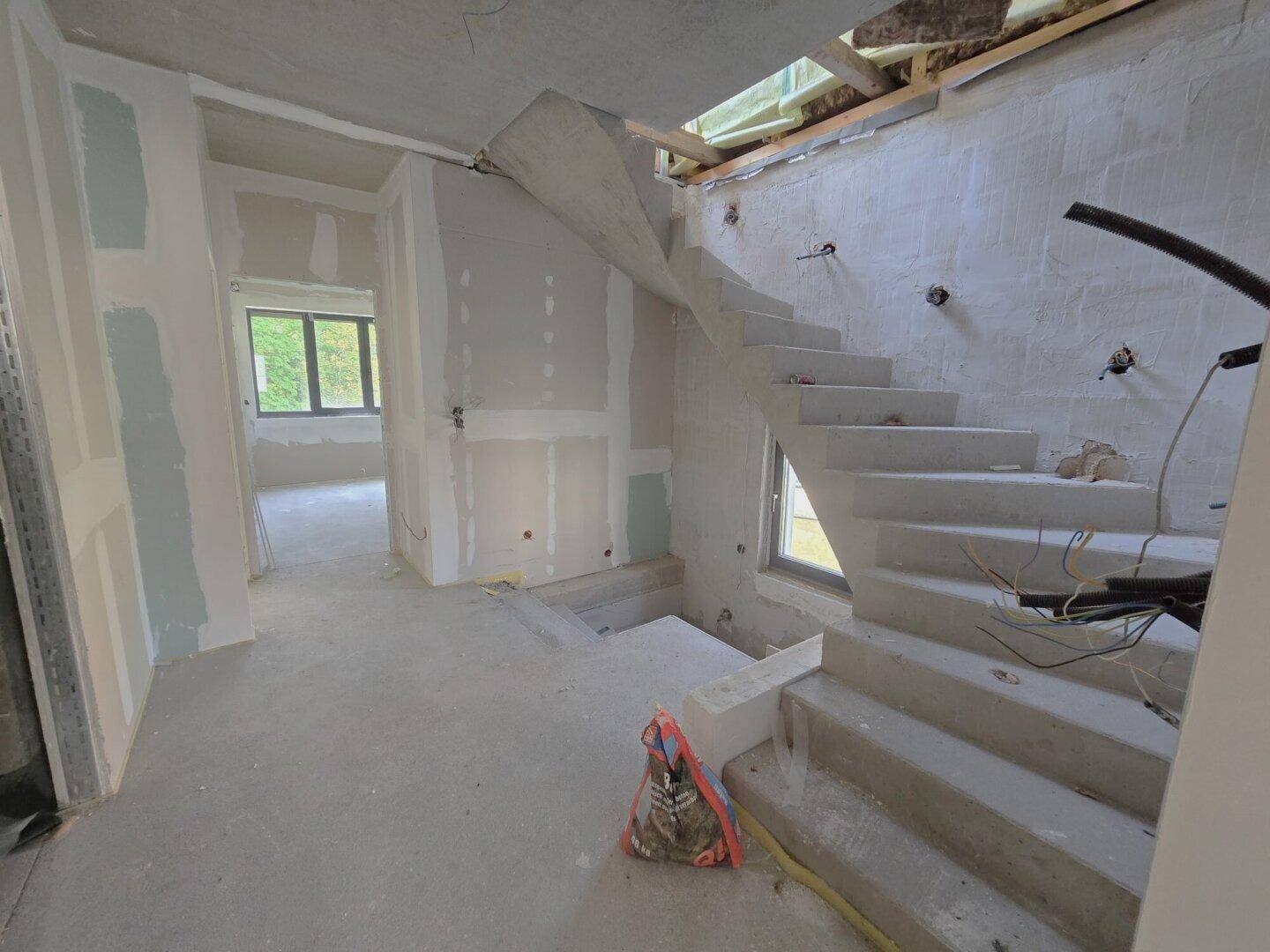 Treppenhaus im Rohbau mit unfertigen Wänden und Betontreppe, bereit für den Ausbau.