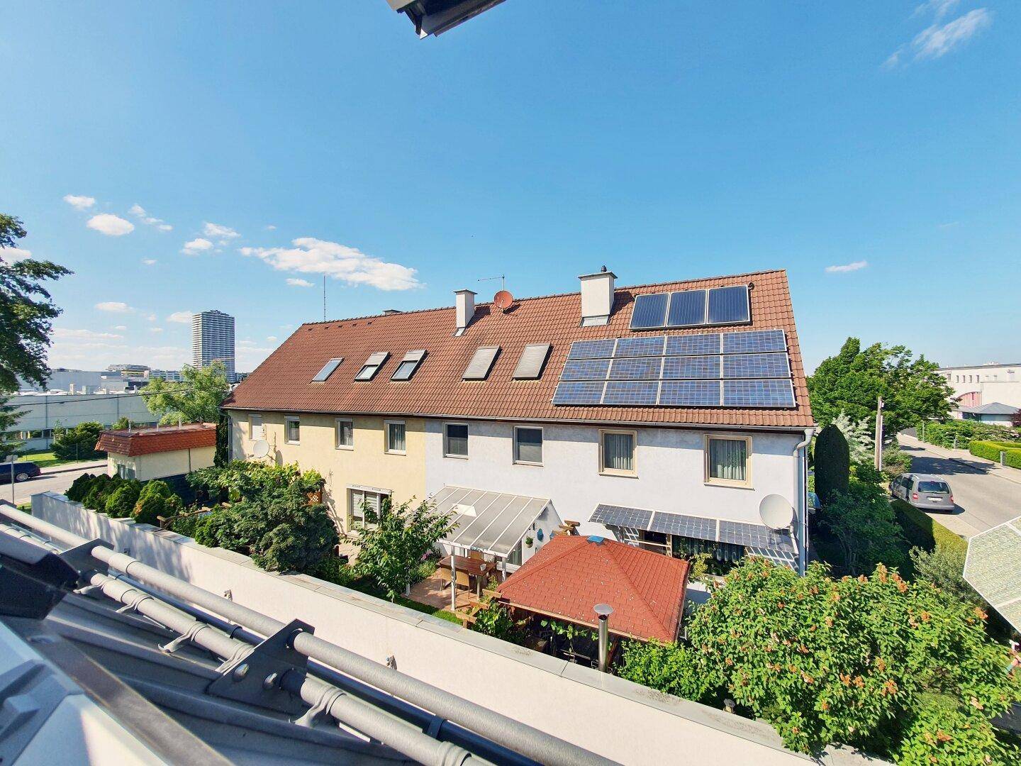 Mehrfamilienhaus mit Solaranlagen auf dem Dach und umliegender Grünfläche.