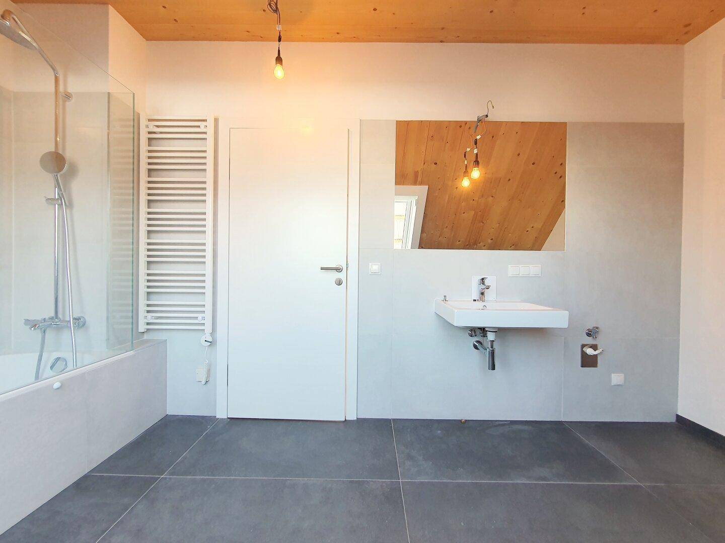 Modernes Badezimmer mit Dusche, Waschbecken und beheiztem Handtuchhalter.