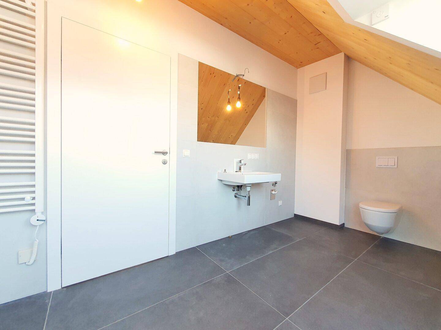 Modernes Badezimmer mit Waschbecken, Toilette und beheiztem Handtuchhalter.