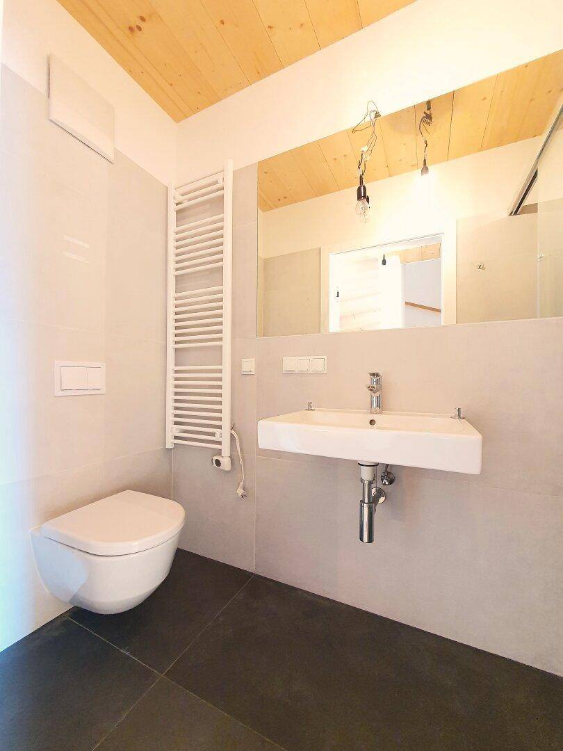 Modernes Badezimmer mit wandhängender Toilette und rechteckigem Waschbecken.