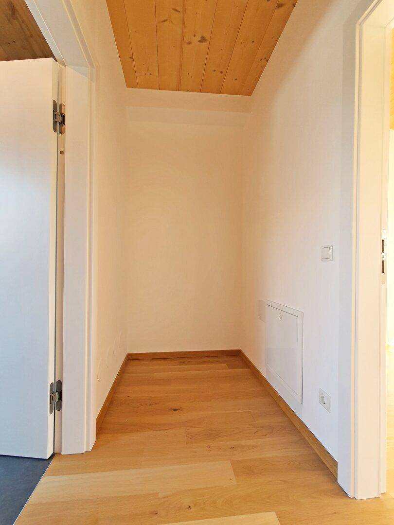 Heller Flur mit Holzboden und weiß gestrichenen Wänden.