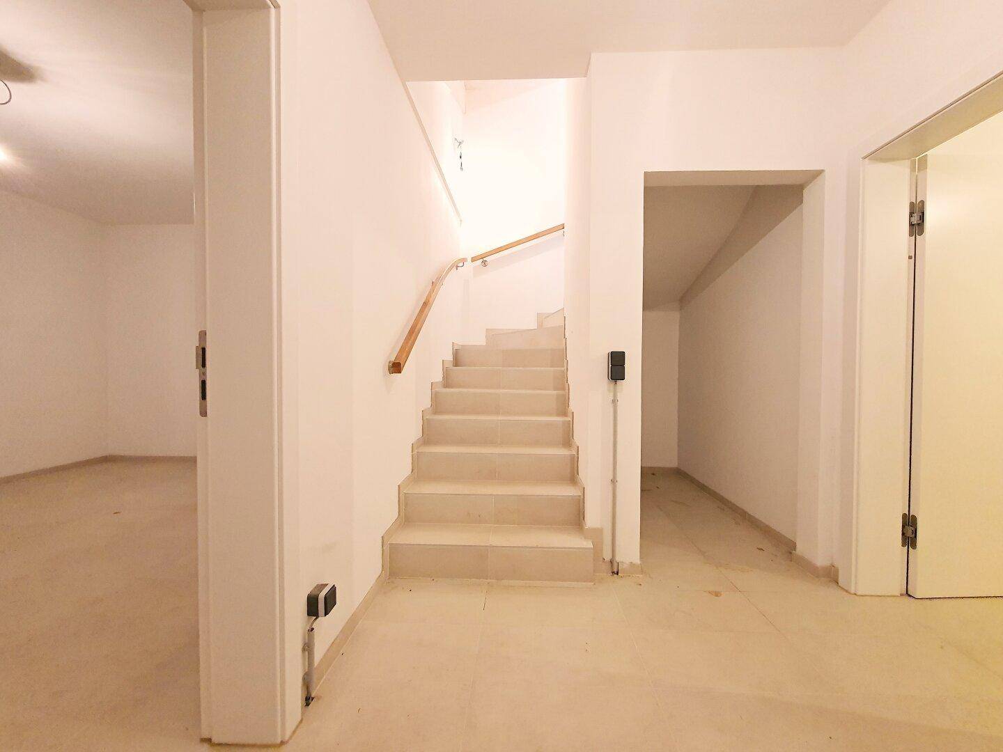 Treppenhaus führt in einen hellen Kellerbereich mit Fliesenboden.