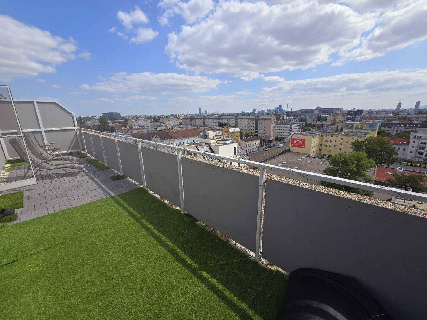 Dachterrasse mit Kunstrasen und weitem Panoramablick über die Stadt.
