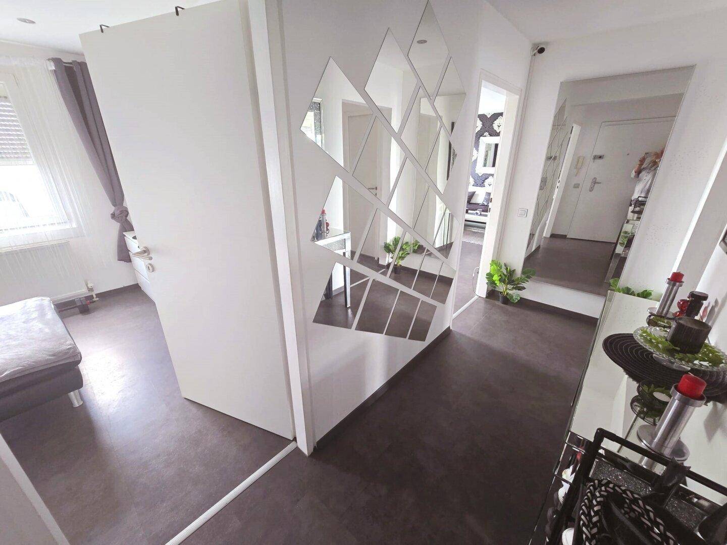Flur mit dekorativer Spiegelwand, die zu einem Schlafzimmer und weiteren Bereichen führt.