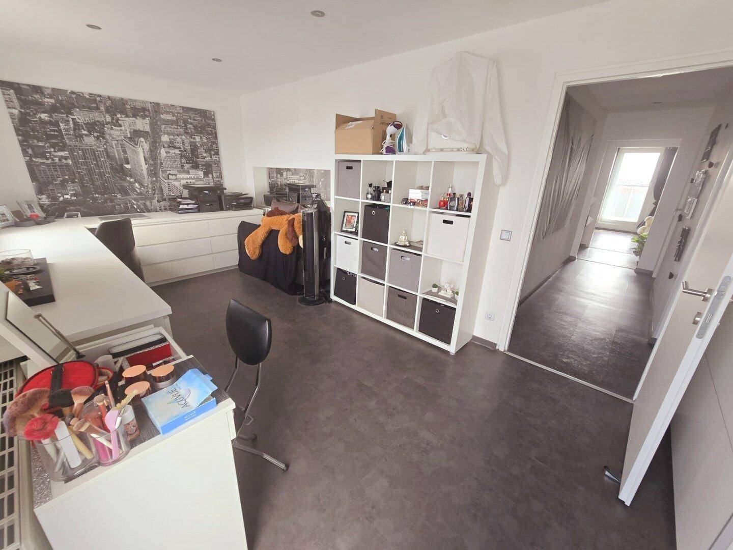 Arbeitszimmer mit Regal und Blick in den Flur, bietet viel Stauraum.