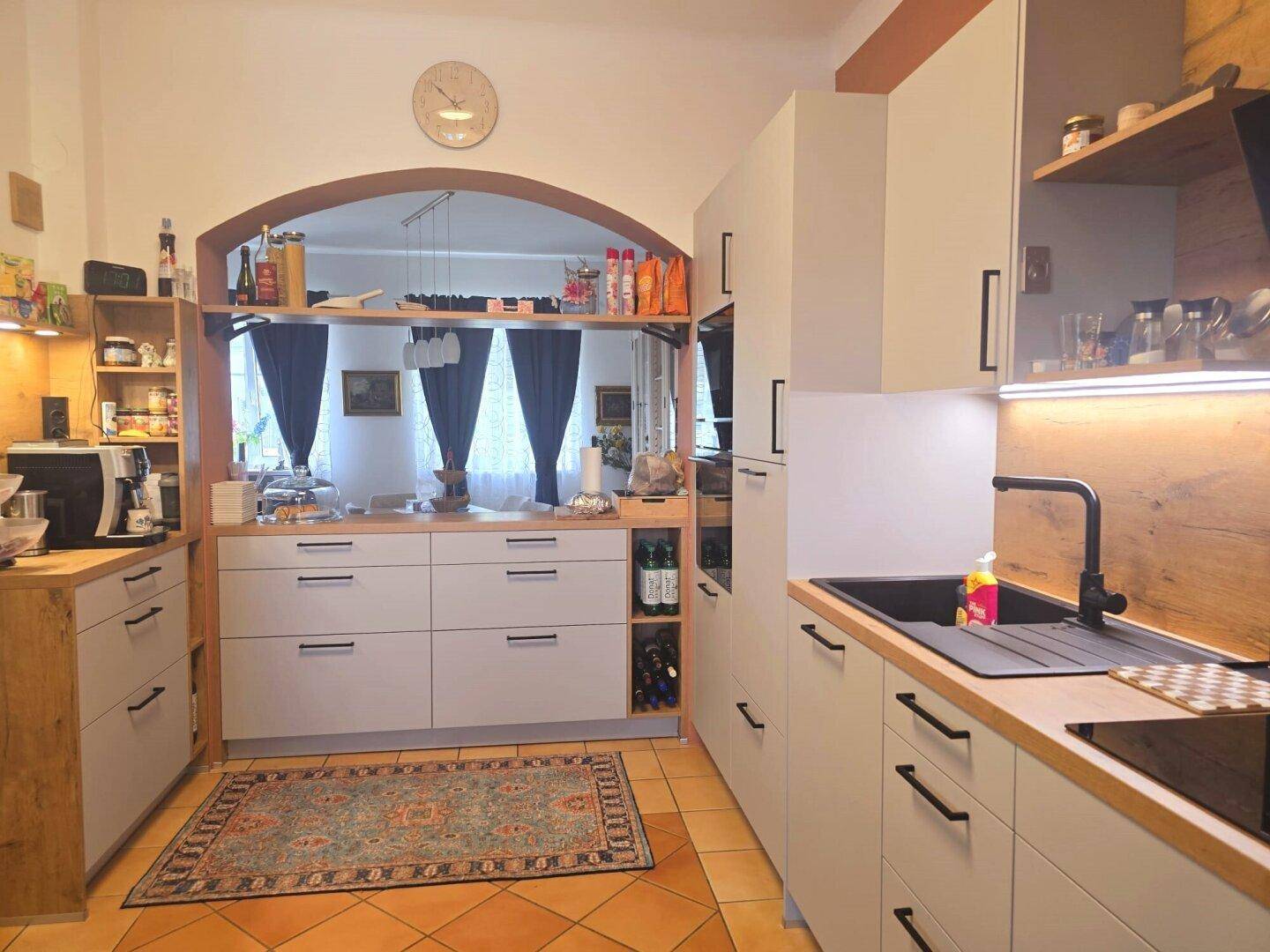 Funktionale Küche mit Holzakzenten, modernen Geräten und Blick in den Essbereich.