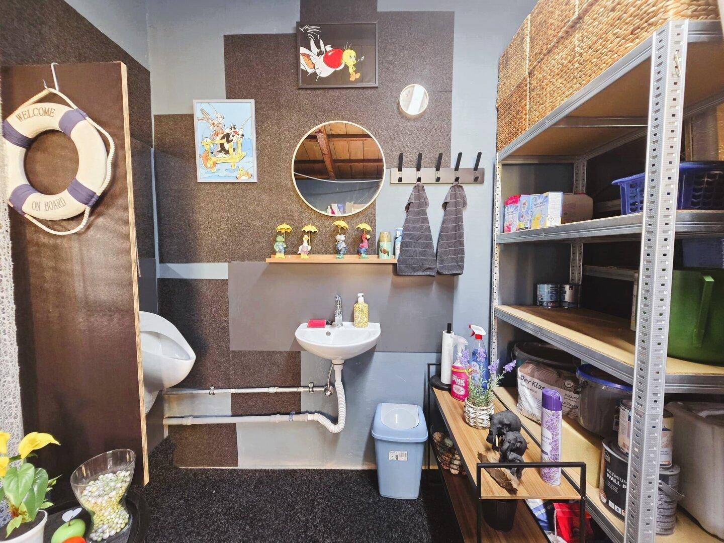 Funktionaler Hauswirtschaftsraum mit Waschbecken, Urinal und Regalen, bietet viel Stauraum.