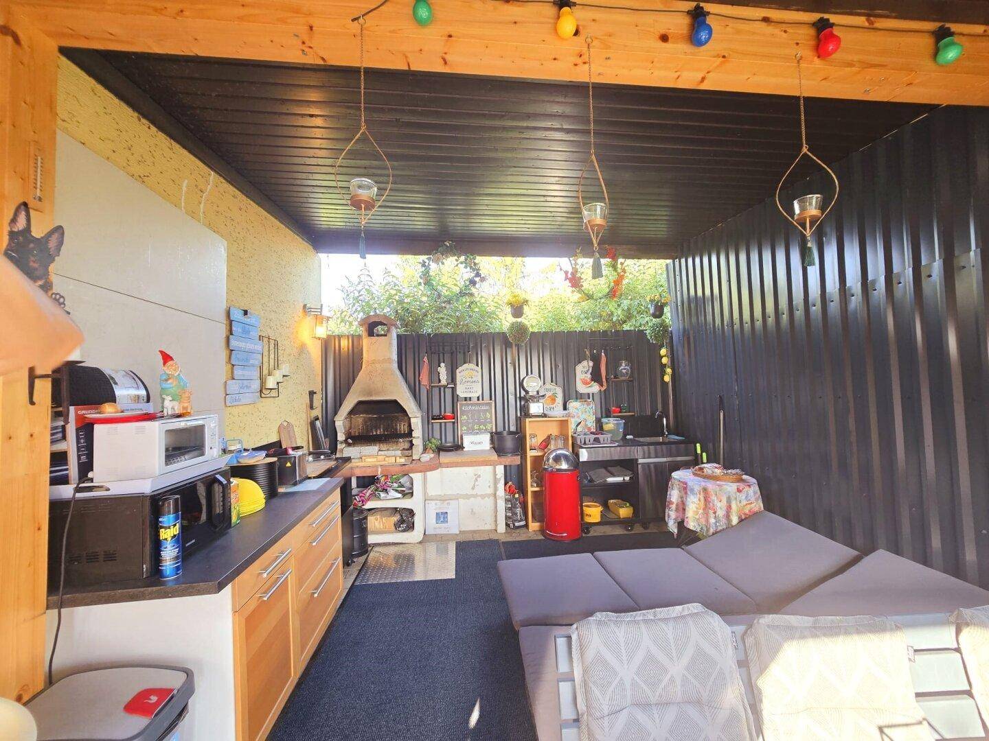 Gemütliche überdachte Terrasse mit voll ausgestatteter Außenküche und bequemen Sitzmöbeln.