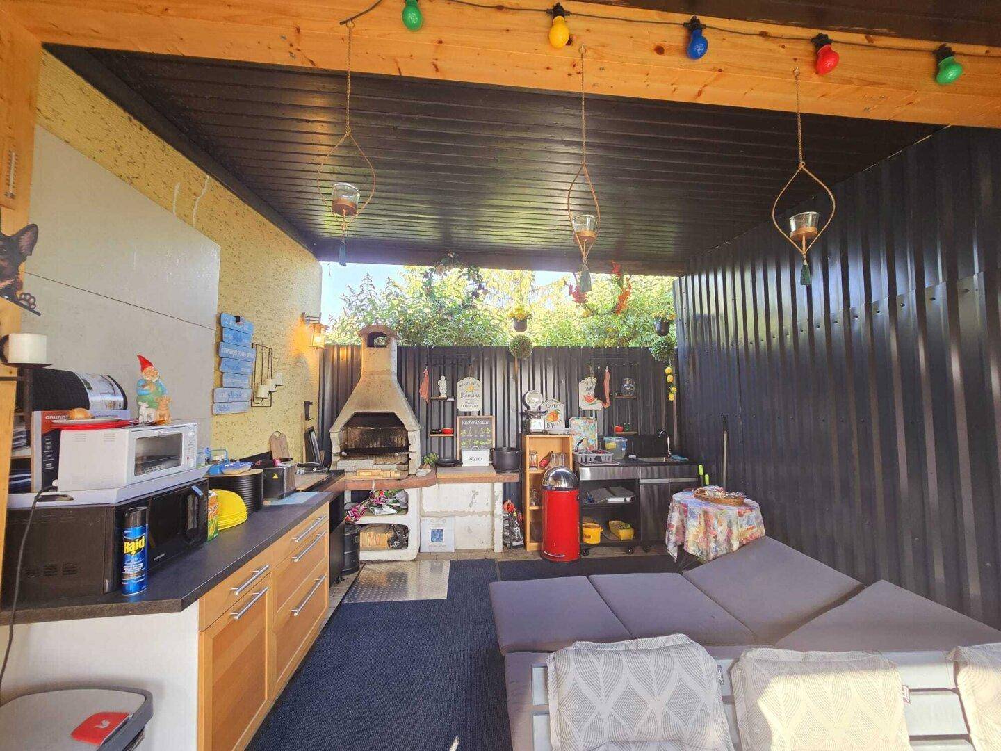Gemütliche überdachte Terrasse mit voll ausgestatteter Außenküche und bequemen Sitzmöbeln.