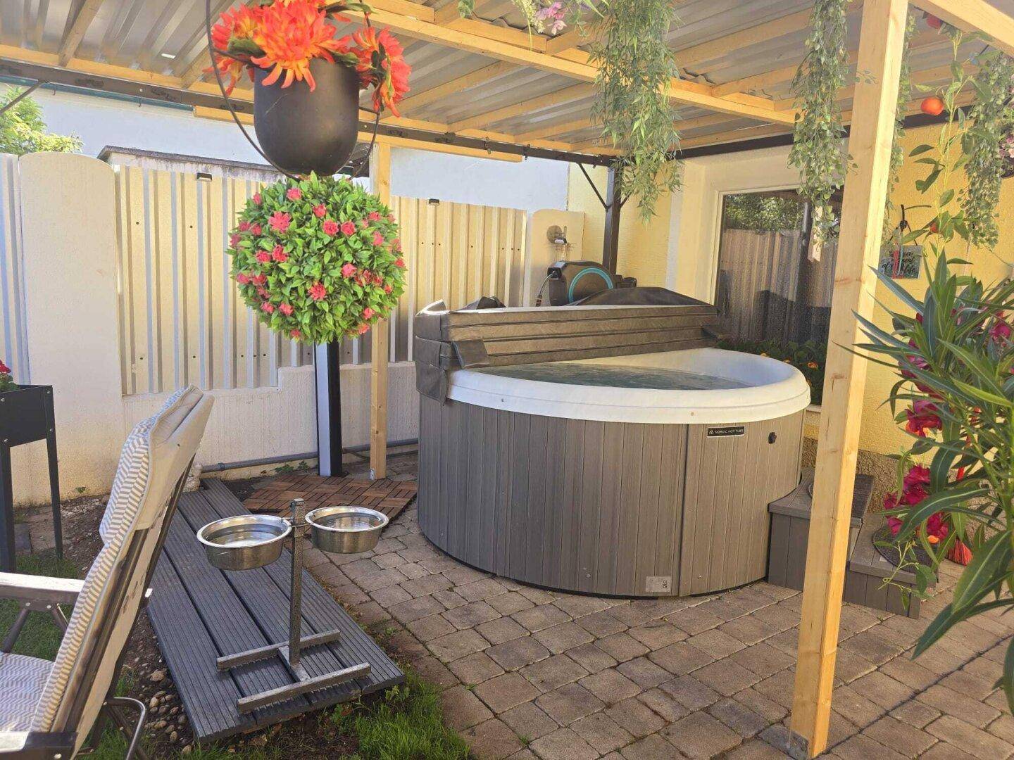 Entspannungsbereich im Freien mit Whirlpool, Holzboden und dekorativen Pflanzen.