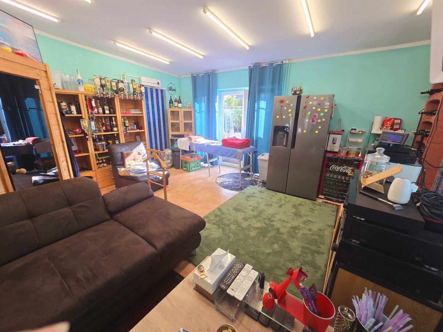 Großer Freizeitraum mit Sofa, zwei Kühlschränken und Barbereich, ideal für Unterhaltung.