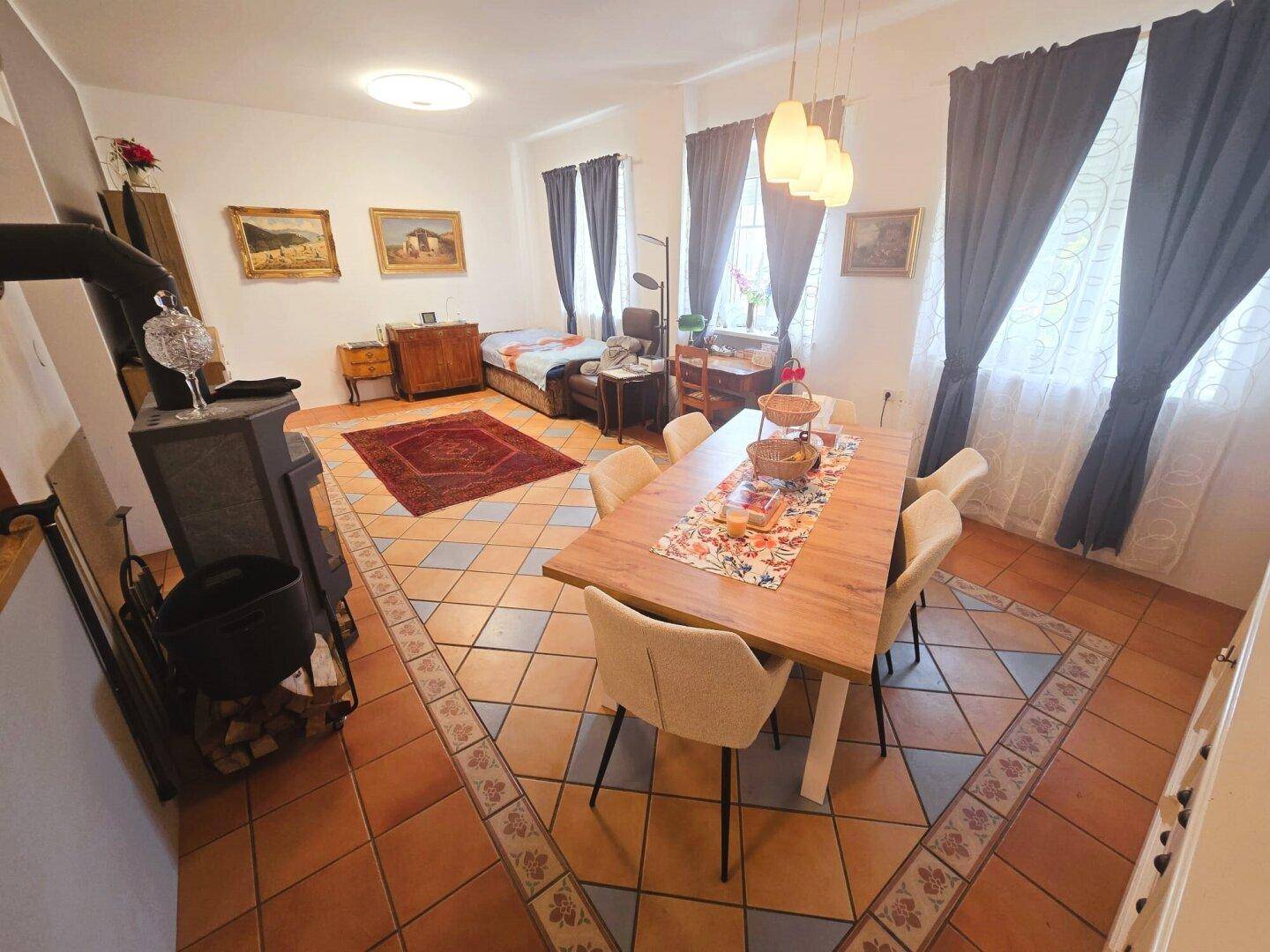 Offener Wohn-Essbereich mit Kaminofen, großem Esstisch und gemütlicher Einrichtung.