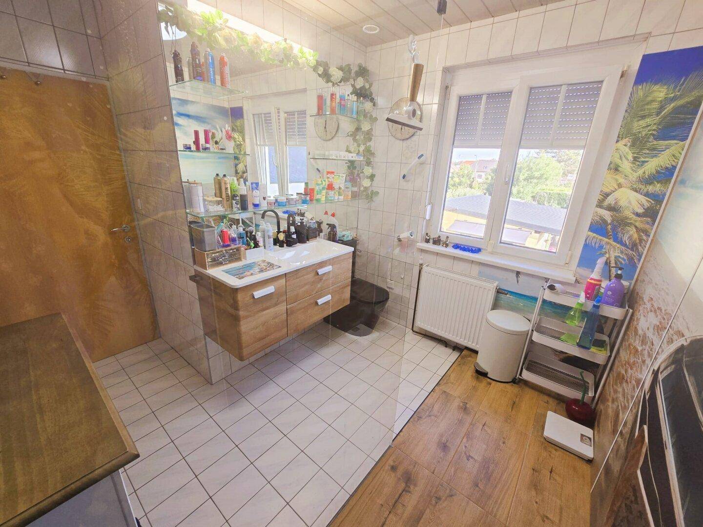 Helles Badezimmer mit modernem Waschtisch, großem Spiegel und Fenster.