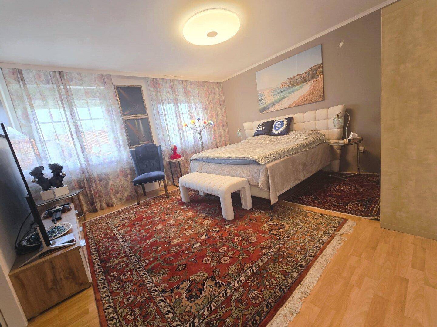 Gemütliches Schlafzimmer mit großem Bett, Teppich und Vorhängen, bietet eine entspannende Atmosphäre.