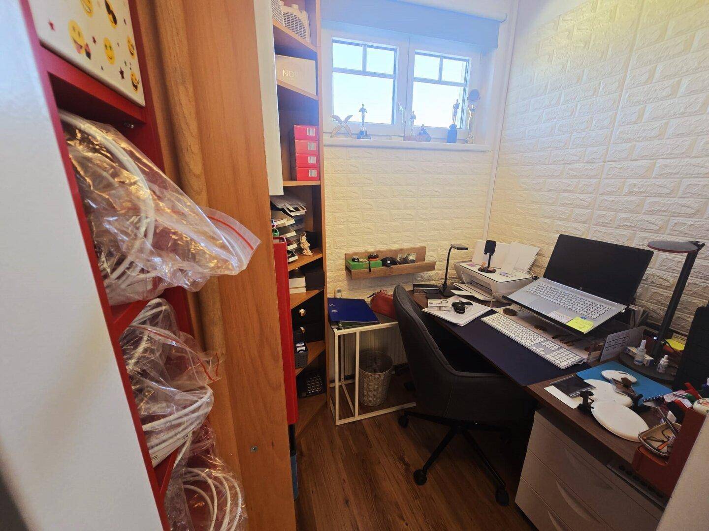 Kleines, funktionales Büro mit Schreibtisch, Laptop und Regalen, ideal für Home-Office.